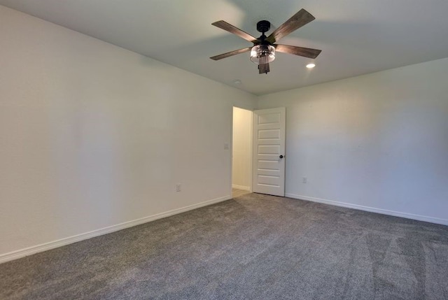 spare room with ceiling fan, baseboards, and dark colored carpet