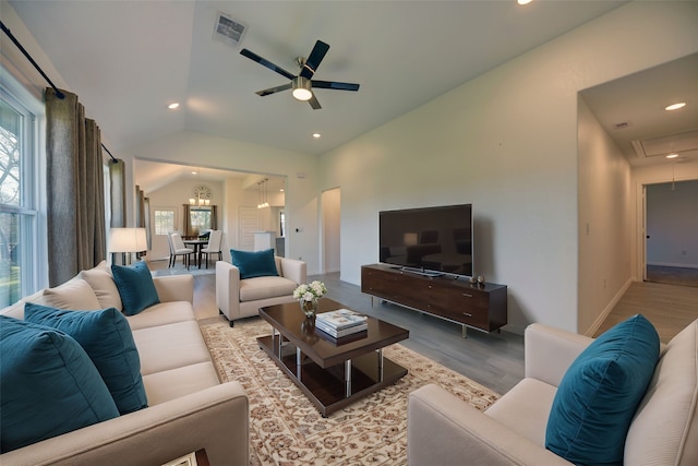 living area with a healthy amount of sunlight, wood finished floors, visible vents, attic access, and vaulted ceiling