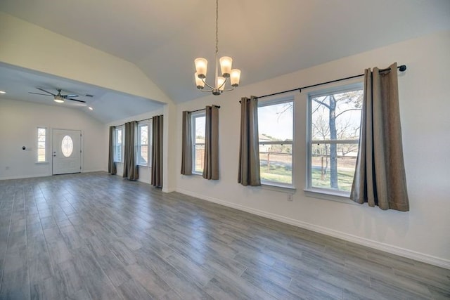 interior space with ceiling fan with notable chandelier, lofted ceiling, dark wood-style floors, and baseboards