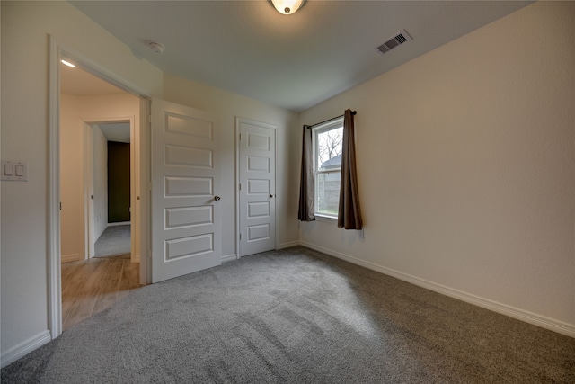 unfurnished bedroom featuring visible vents, baseboards, and carpet