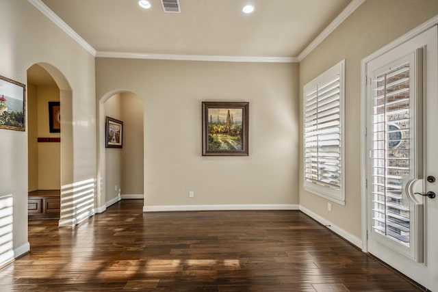 unfurnished room with visible vents, crown molding, baseboards, dark wood finished floors, and arched walkways