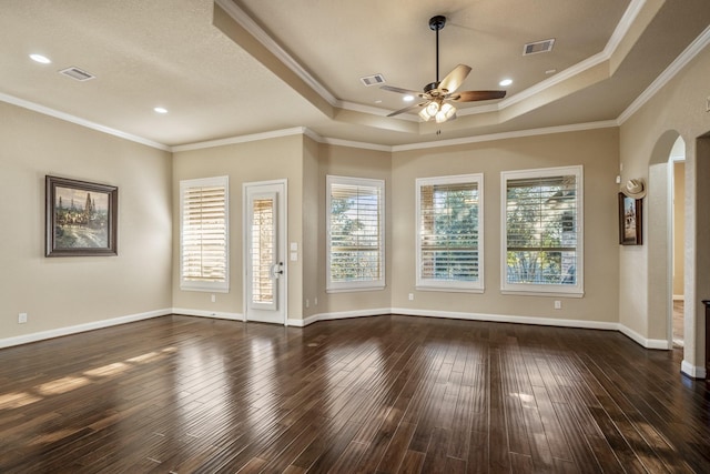 unfurnished room featuring visible vents, arched walkways, dark wood-style flooring, ceiling fan, and a raised ceiling