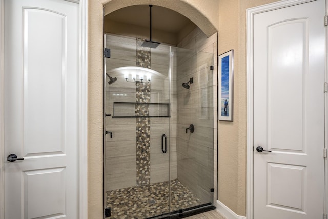 full bath featuring a shower stall and a textured wall