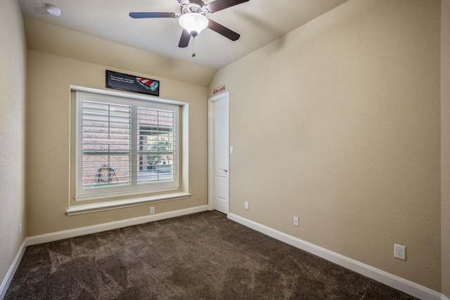 empty room featuring dark carpet, lofted ceiling, baseboards, and ceiling fan