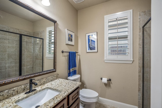 bathroom with vanity, toilet, baseboards, and a tile shower