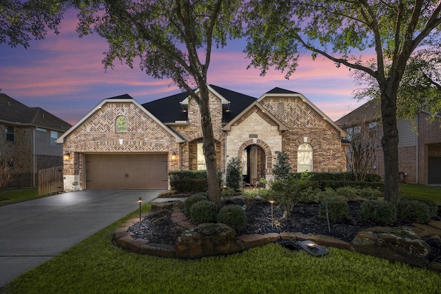 french country home with brick siding, an attached garage, and concrete driveway