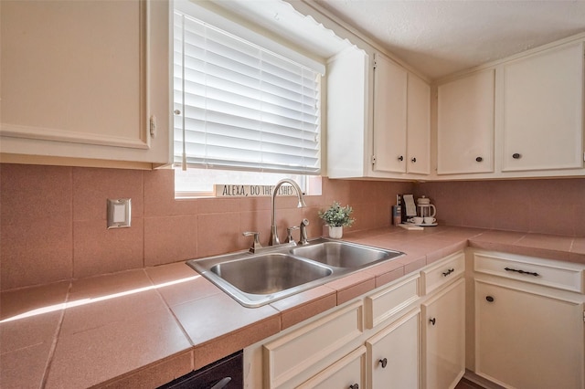 kitchen with white cabinetry, tile countertops, tasteful backsplash, and a sink