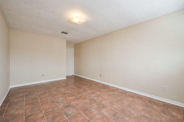 spare room featuring visible vents, a textured ceiling, and baseboards