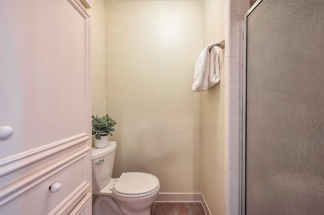 bathroom with tile patterned flooring, a shower stall, toilet, and baseboards