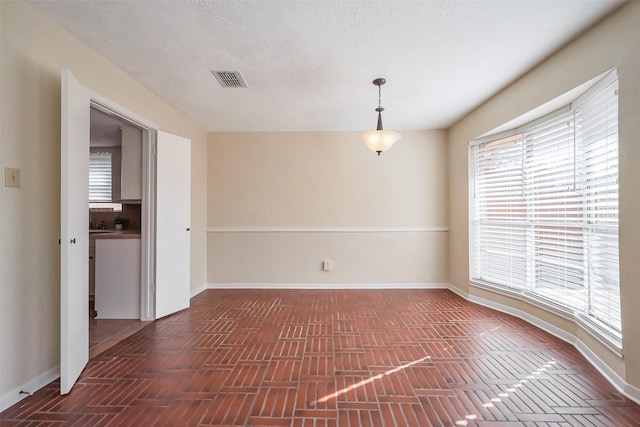 spare room with visible vents, a textured ceiling, and baseboards