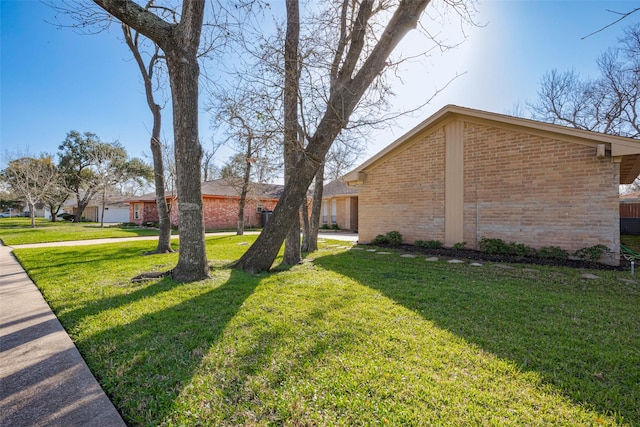 exterior space with brick siding and a yard