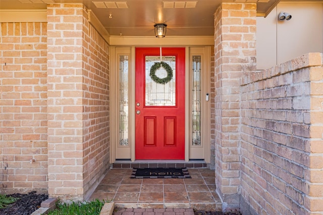 view of exterior entry featuring brick siding