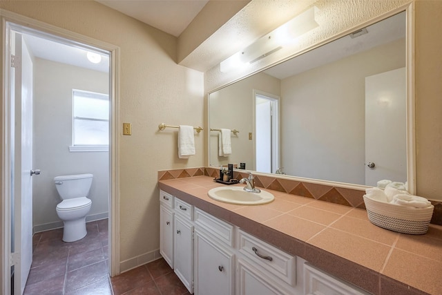 bathroom featuring vanity, visible vents, baseboards, tile patterned flooring, and toilet