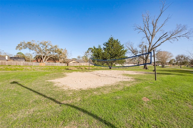 view of home's community with a yard, volleyball court, and fence