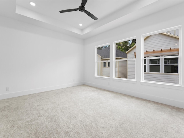 unfurnished room with a ceiling fan, baseboards, recessed lighting, a raised ceiling, and carpet flooring