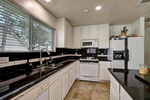 kitchen featuring visible vents, white cabinets, white appliances, and a sink