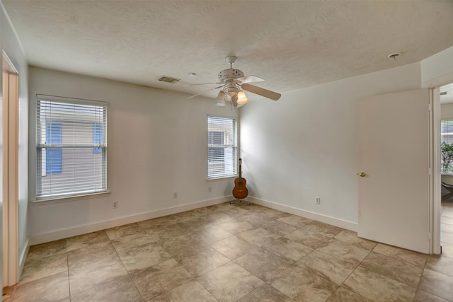 empty room featuring visible vents, baseboards, a textured ceiling, and ceiling fan