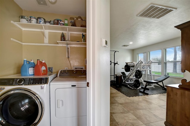 laundry area with light tile patterned floors, visible vents, laundry area, and washing machine and clothes dryer