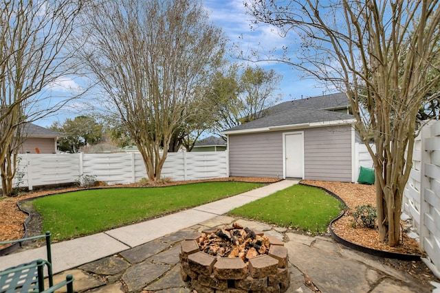 view of yard featuring an outbuilding, a fire pit, and a fenced backyard