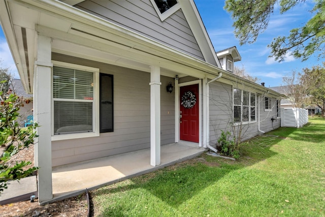 doorway to property with a porch and a lawn