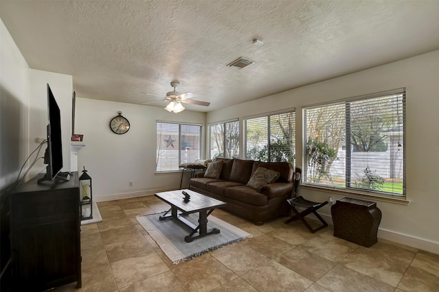 living room with visible vents, baseboards, a textured ceiling, and a ceiling fan