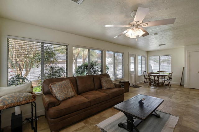 living area with baseboards, a textured ceiling, and a ceiling fan