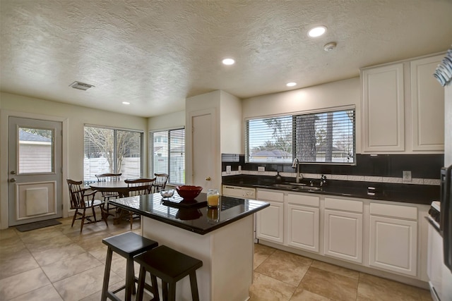 kitchen with a sink, a kitchen breakfast bar, a kitchen island, and white cabinets