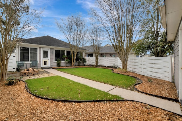 exterior space with a fenced backyard, an outdoor fire pit, and a front yard