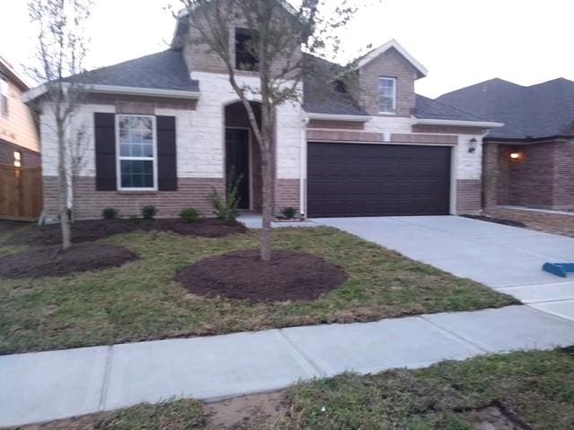 view of front of home featuring brick siding, driveway, a garage, and fence