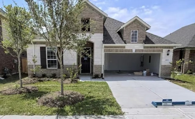 view of front of house featuring driveway, roof with shingles, a front yard, an attached garage, and brick siding