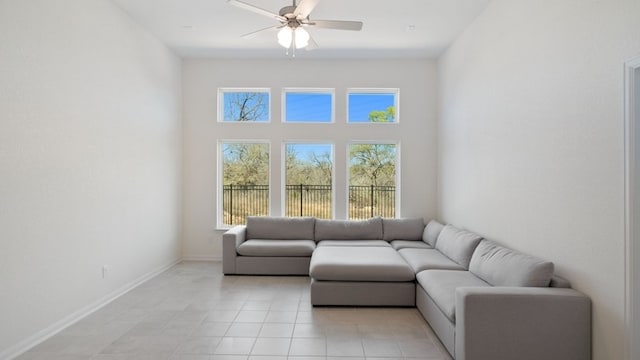 living area featuring light tile patterned flooring, baseboards, and ceiling fan