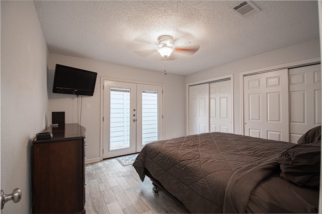 bedroom featuring a ceiling fan, visible vents, light wood-style flooring, access to exterior, and multiple closets