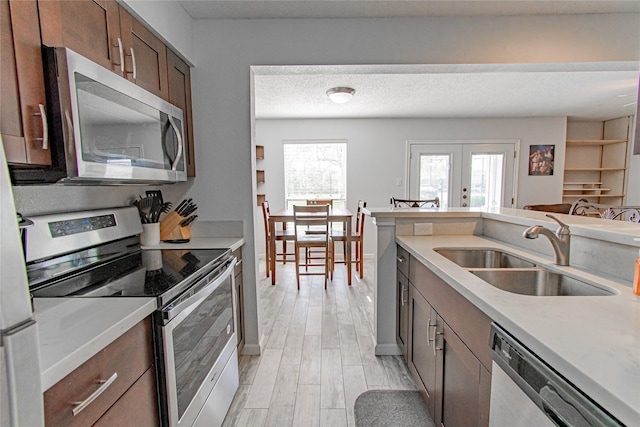 kitchen featuring a sink, stainless steel appliances, light countertops, a textured ceiling, and light wood-type flooring