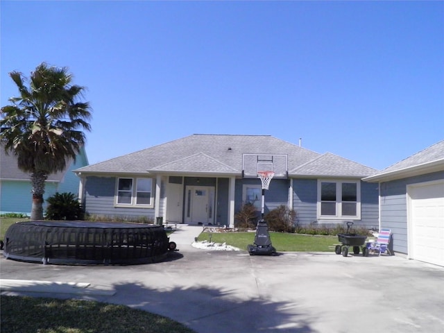 view of front facade featuring concrete driveway, a front yard, and a shingled roof