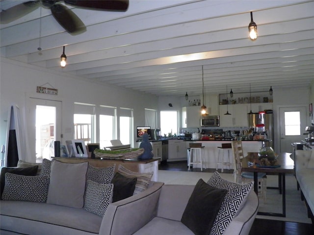 living room with a wealth of natural light, beamed ceiling, and ceiling fan