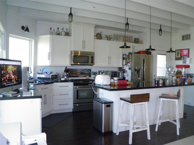 kitchen featuring visible vents, beam ceiling, dark countertops, white cabinetry, and appliances with stainless steel finishes