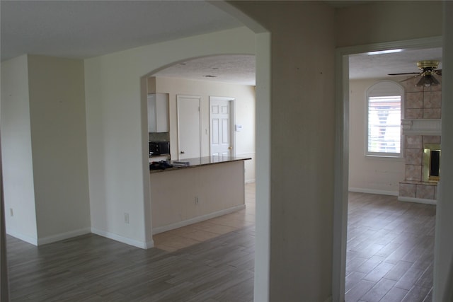 interior space with light wood-style flooring, baseboards, arched walkways, and a textured ceiling