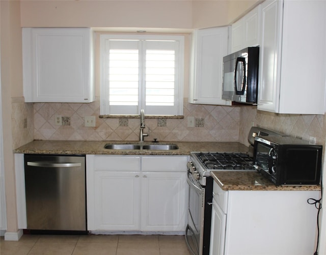 kitchen with backsplash, light tile patterned flooring, white cabinets, stainless steel appliances, and a sink