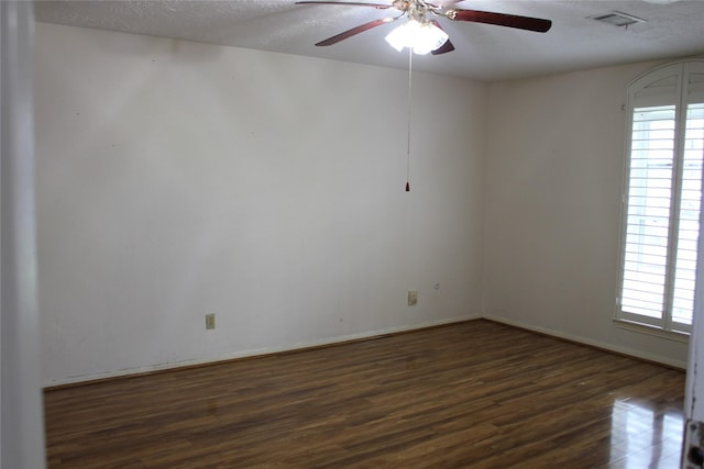 unfurnished room featuring visible vents, plenty of natural light, a textured ceiling, and dark wood-style flooring