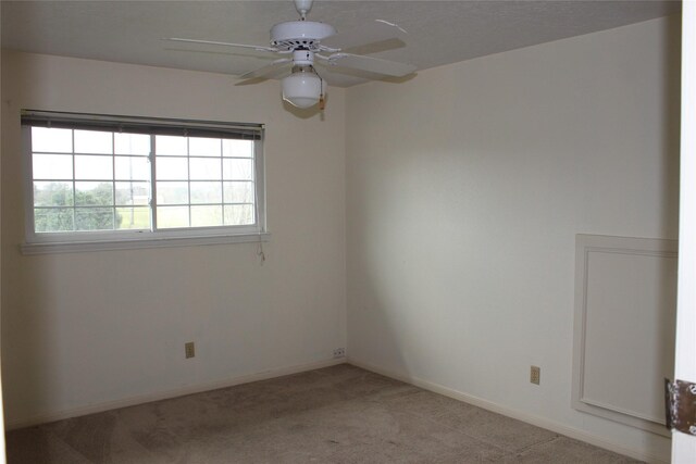 unfurnished room with light colored carpet, baseboards, and ceiling fan