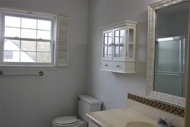 bathroom featuring a shower with door, toilet, and vanity