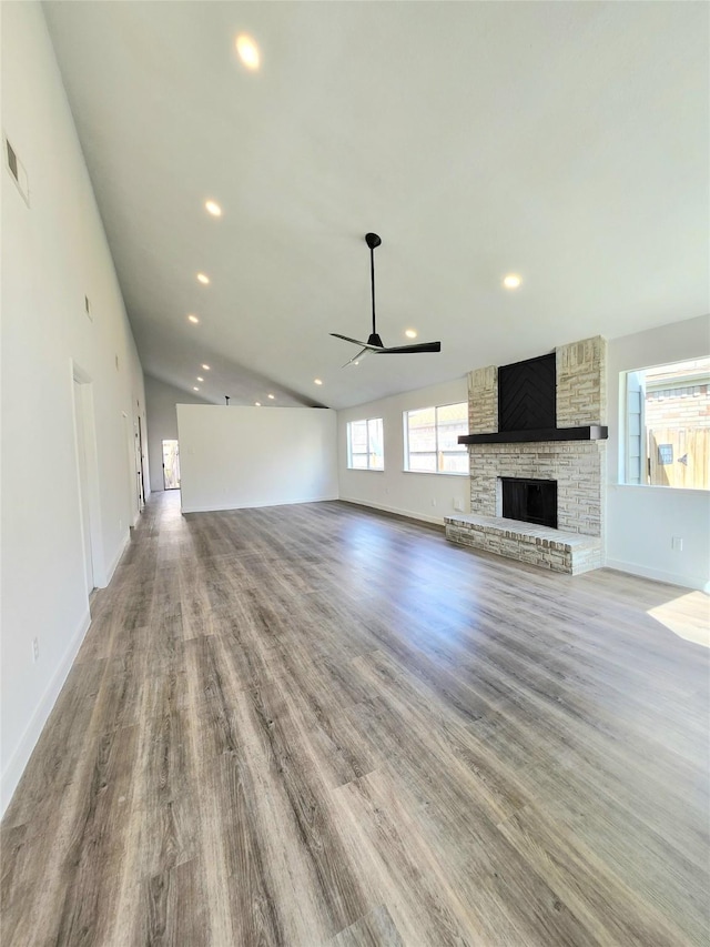 unfurnished living room with wood finished floors, a ceiling fan, a fireplace, recessed lighting, and vaulted ceiling