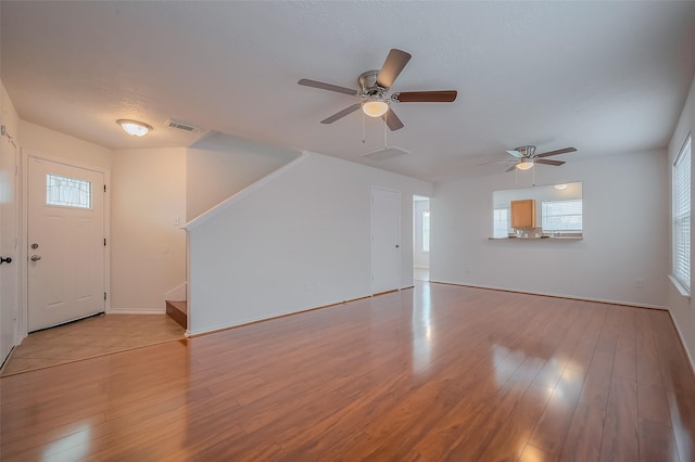 unfurnished living room with visible vents, plenty of natural light, baseboards, and light wood-style flooring