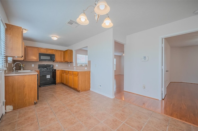 kitchen featuring visible vents, brown cabinets, black appliances, a sink, and light countertops