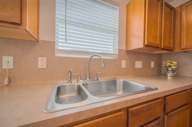 kitchen featuring light countertops, brown cabinets, tasteful backsplash, and a sink