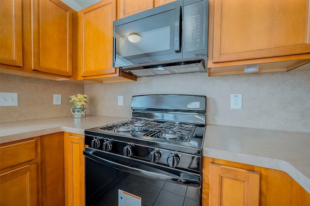 kitchen featuring black appliances, brown cabinetry, light countertops, and tile patterned floors