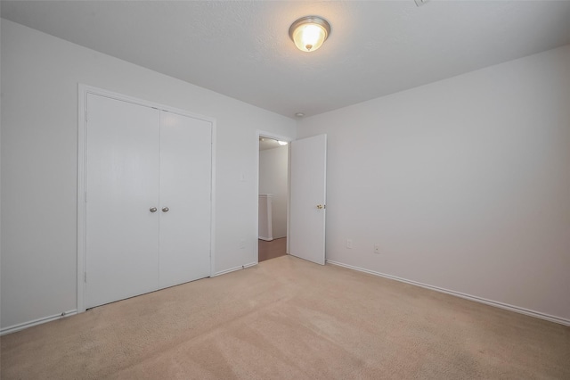 unfurnished bedroom with a closet, light carpet, and a textured ceiling