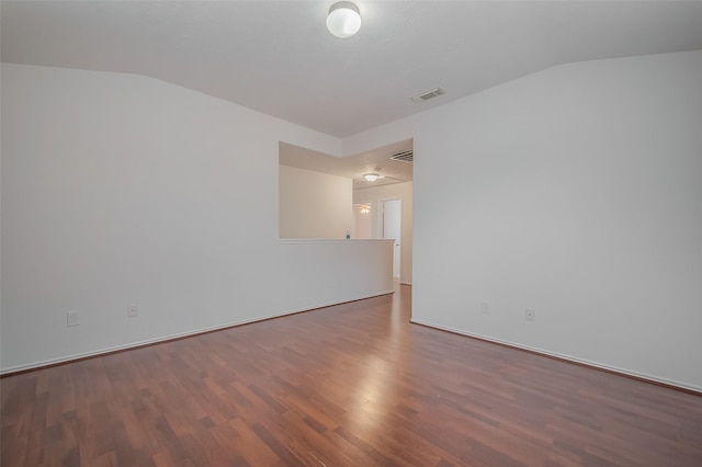 spare room with vaulted ceiling, wood finished floors, and visible vents