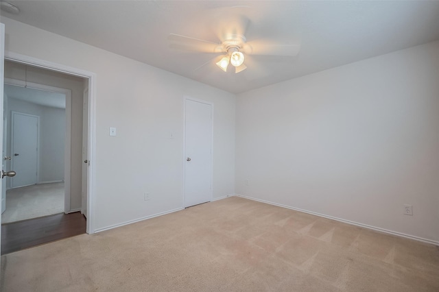 unfurnished room featuring a ceiling fan, light colored carpet, and baseboards