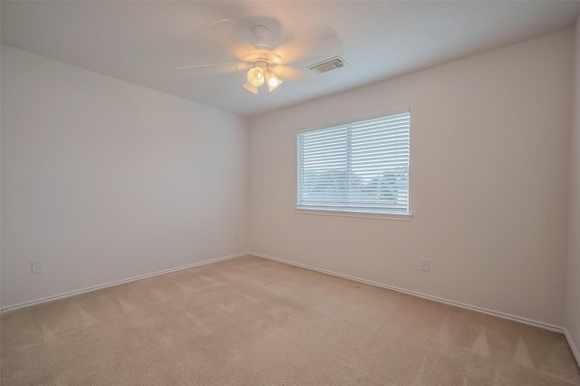 unfurnished room featuring light carpet, visible vents, baseboards, and a ceiling fan